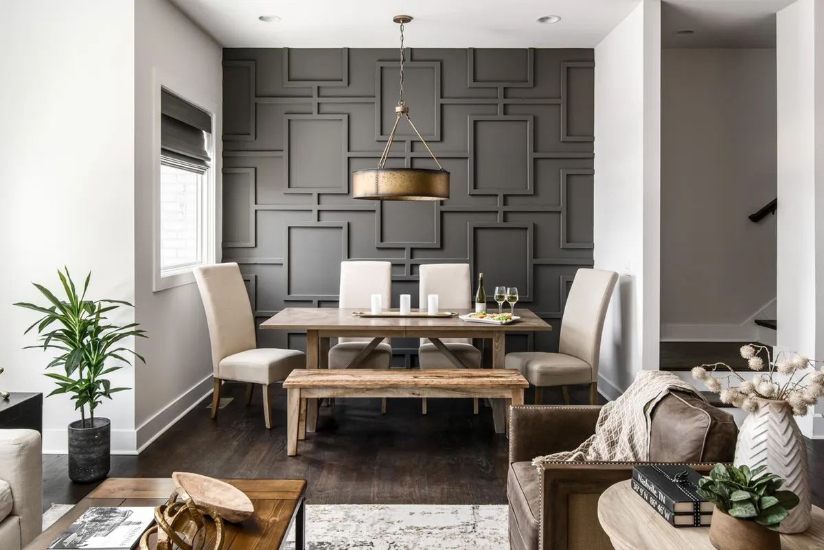 A formal dining area featuring a stylish dining table, elegant chandelier, textured accent wall, lush potted plant, and thoughtfully arranged seating. The mood is warm and inviting, perfect for both family meals and sophisticated entertaining.