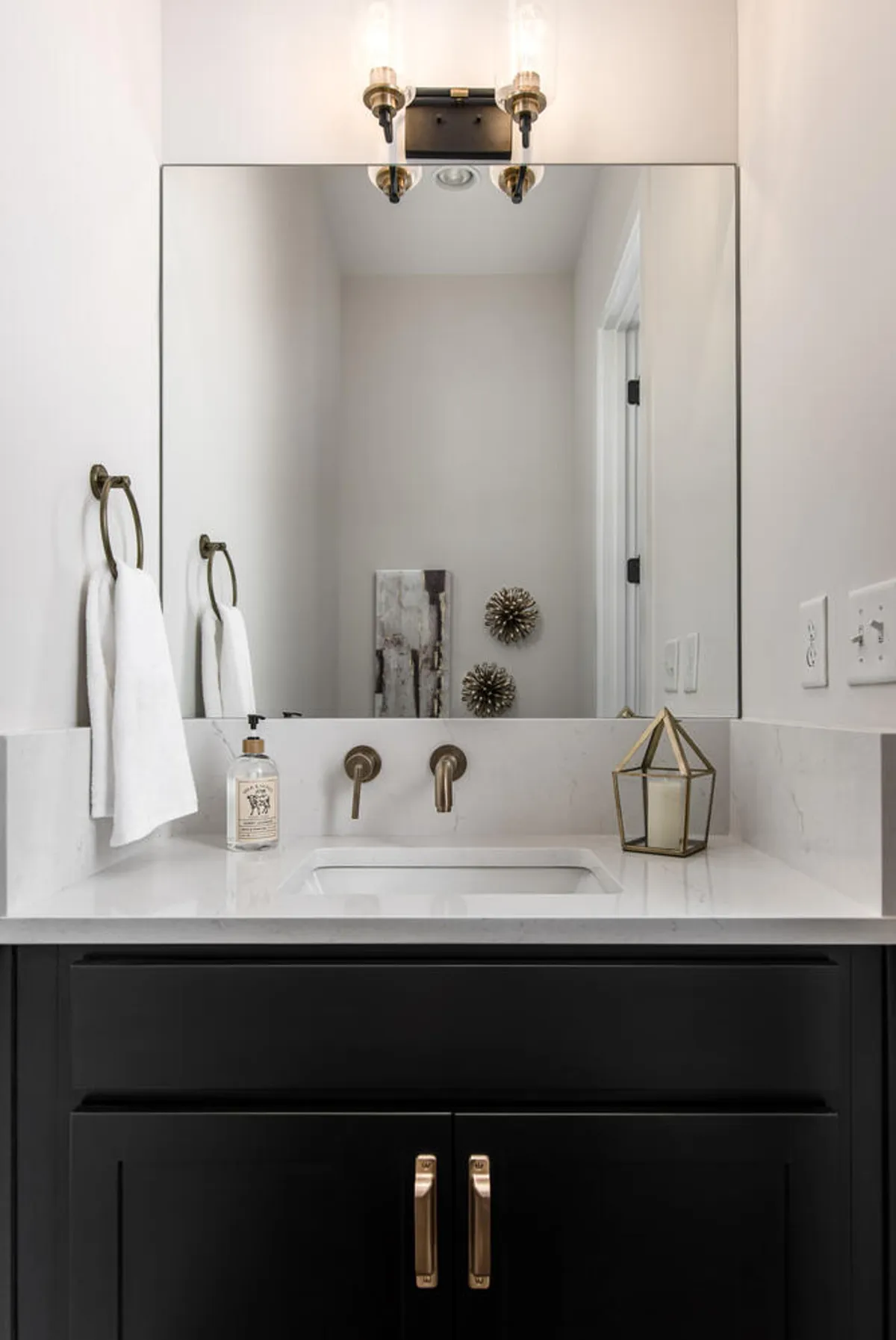 A sophisticated vanity countertop with a wide mirror and elegant light fixtures, complemented by decorative elements that evoke a calm, hotel-like atmosphere. The clean lines and refined surfaces suggest a high level of care and attention to guest comfort.