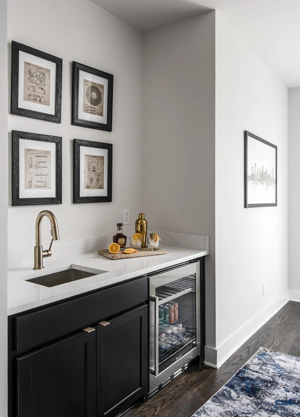 A sleek indoor wet bar area with a modern sink, drink garnishes, and framed artwork, creating a welcoming environment for mixing cocktails and entertaining guests. The cozy and elegant atmosphere hints at seamless transitions between indoor and rooftop gatherings.