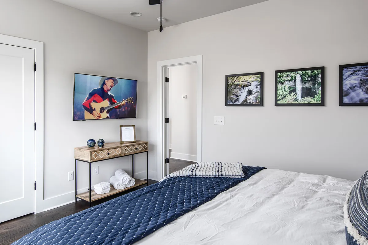 A cozy king bedroom with a quilted navy bedspread, tasteful wall art, and a wooden console. The space feels both serene and intimate, with soft lighting creating a restful ambiance.